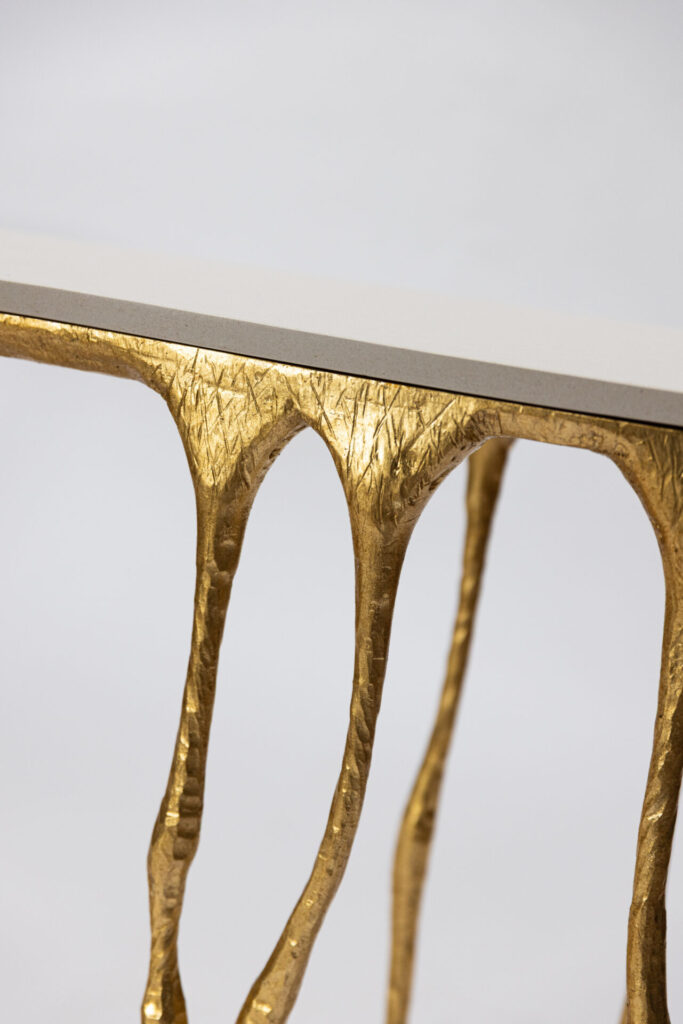 Close-up of a gold textured metal table leg supporting a white tabletop.