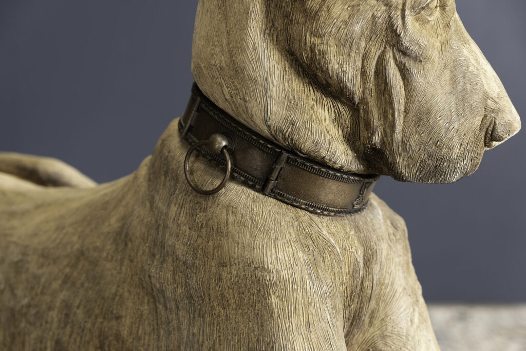 Close-up of a dog statue's neck wearing a leather collar with a metal ring attached