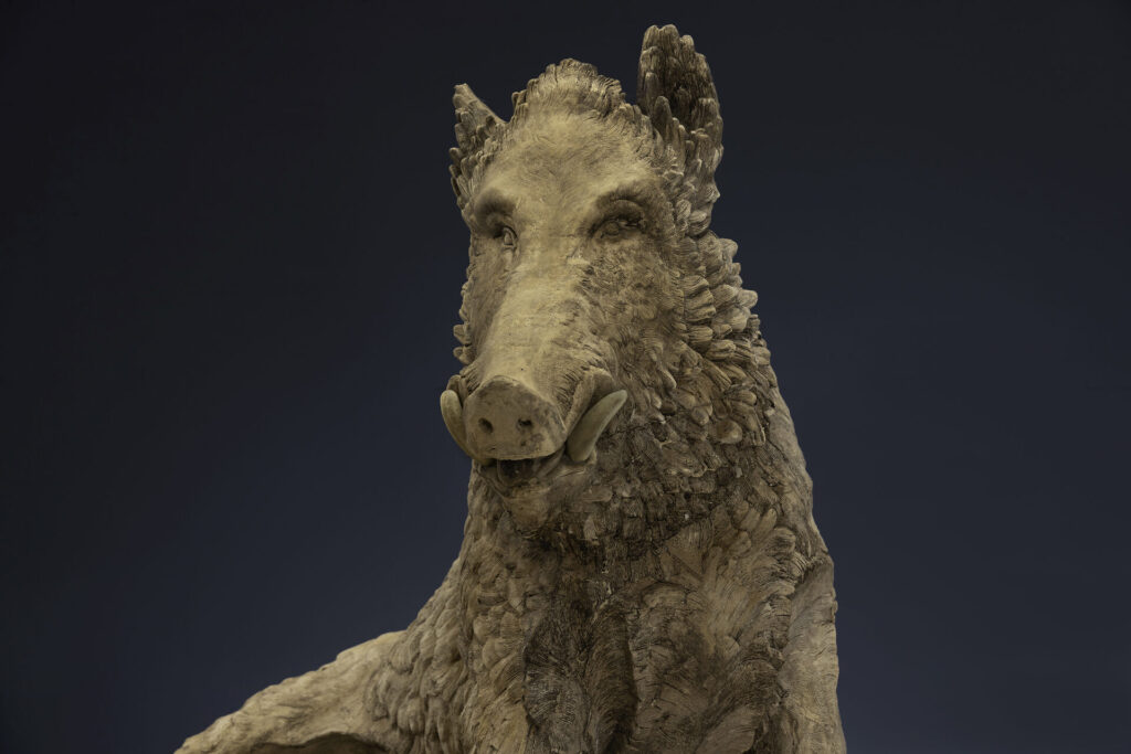 Close-up of a textured stone dinosaur statue head and neck against a dark gradient background.