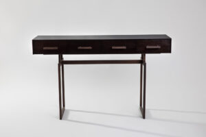 Our Channon console table with drawers - Dark wood desk with four drawers and a slim metal frame, set against a light gray background.