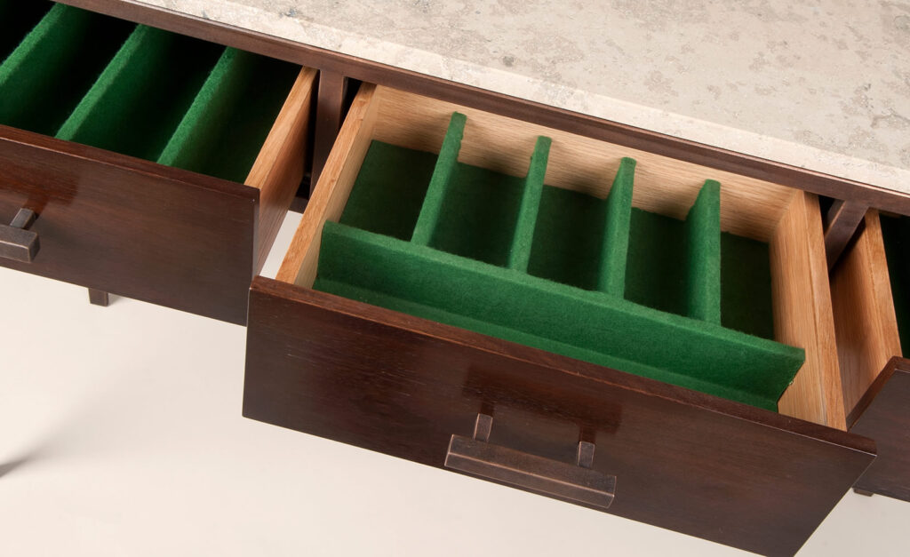 Open wooden drawer with green felt dividers for organizing items